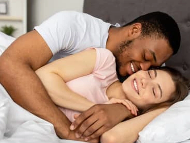 A couple lying together in bed in warm morning light, from the vendor's lifestyle artwork